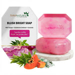 Two pink hexagonal bars of soap stacked on a white marble coaster, with the white branded box behind them and papaya slices, green leaves, and crystals styled in front on a white background.