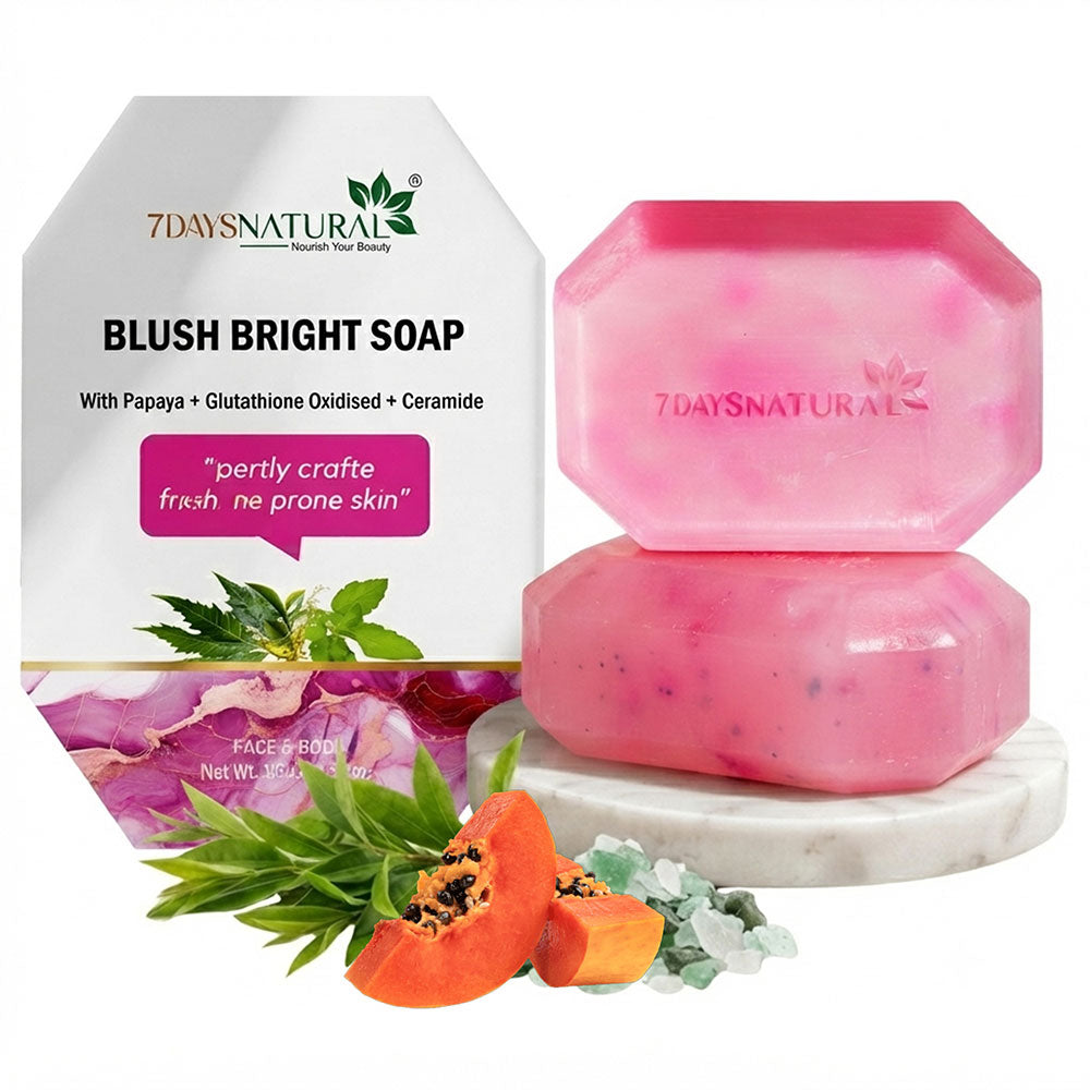 Two pink hexagonal bars of soap stacked on a white marble coaster, with the white branded box behind them and papaya slices, green leaves, and crystals styled in front on a white background.