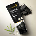 Charcoal peel-off mask packaging with charcoal pieces and leaves on a light background
